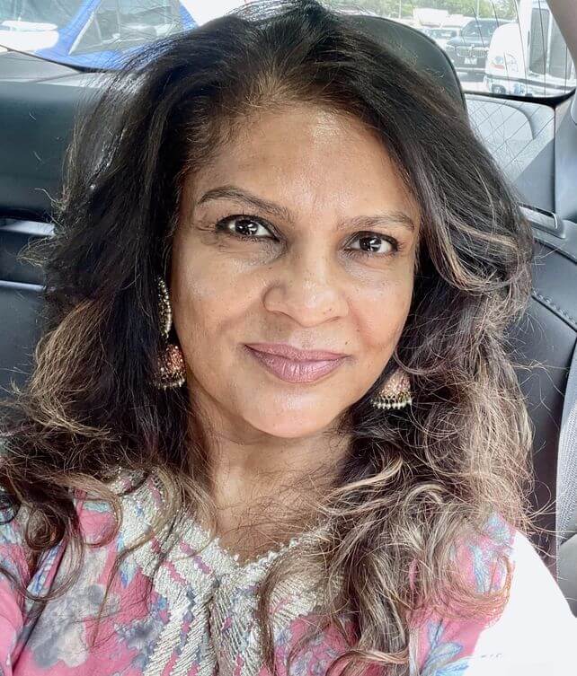 A woman with long hair sitting in the back of a car.