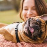 A woman is holding her dog and smiling.