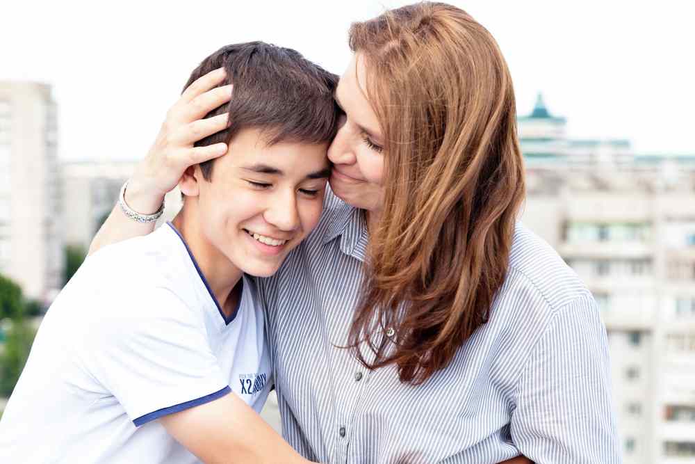 A woman and a boy are hugging each other.