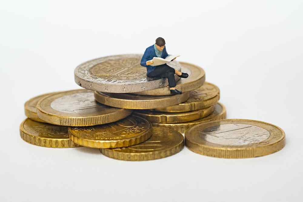 A small figurine sitting on top of some gold coins.