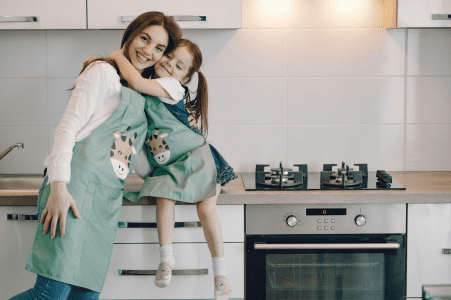 A woman and child in the kitchen hugging.