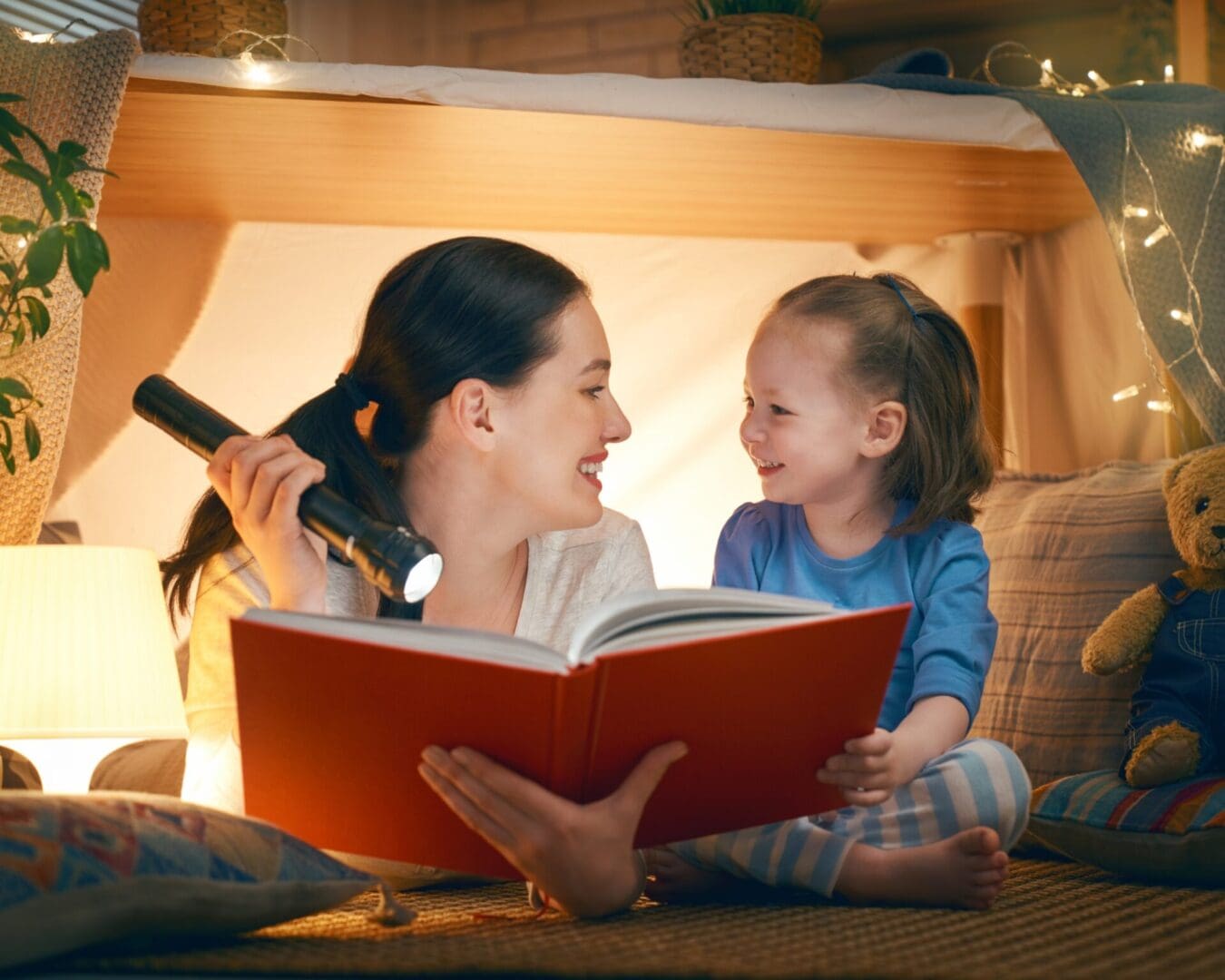 A mother and daughter, both captivated by a children's book, enjoy a refreshing perspective as they read together in bed.