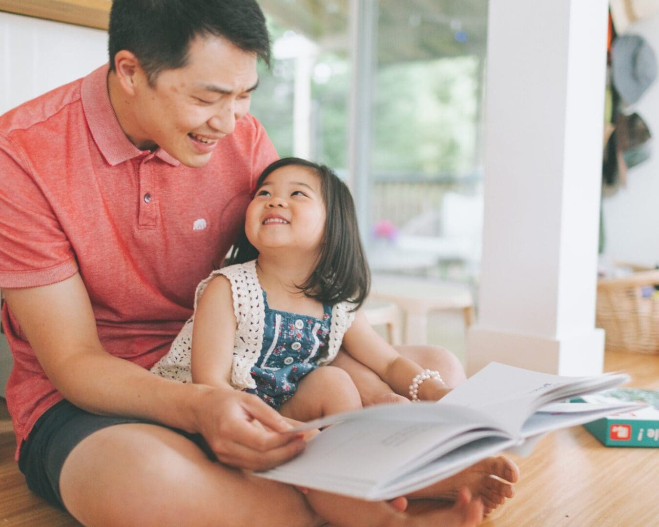 A children's book author and his daughter reading a book in the living room.