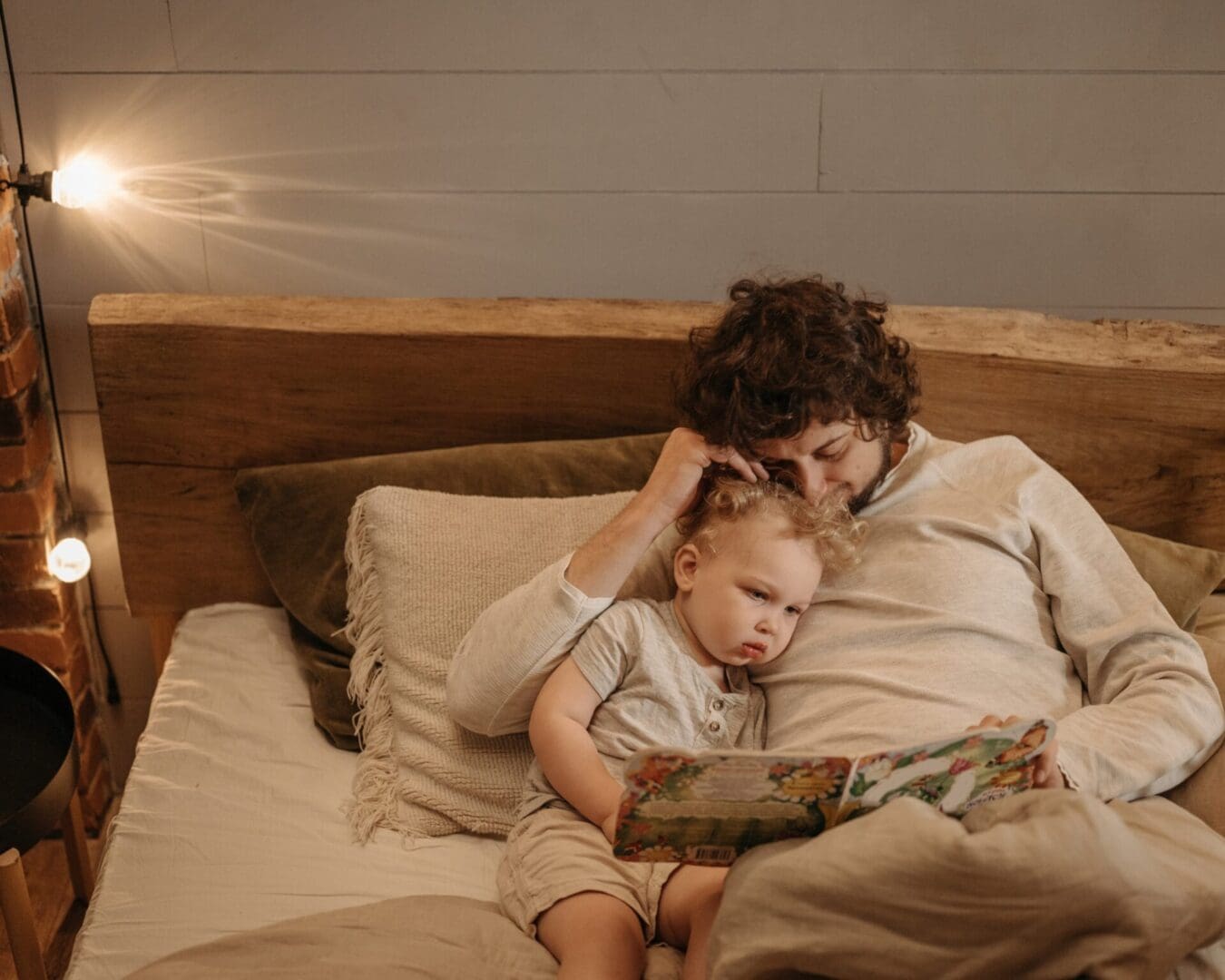 A children's book author reading a book to his child in bed, offering a fresh perspective.