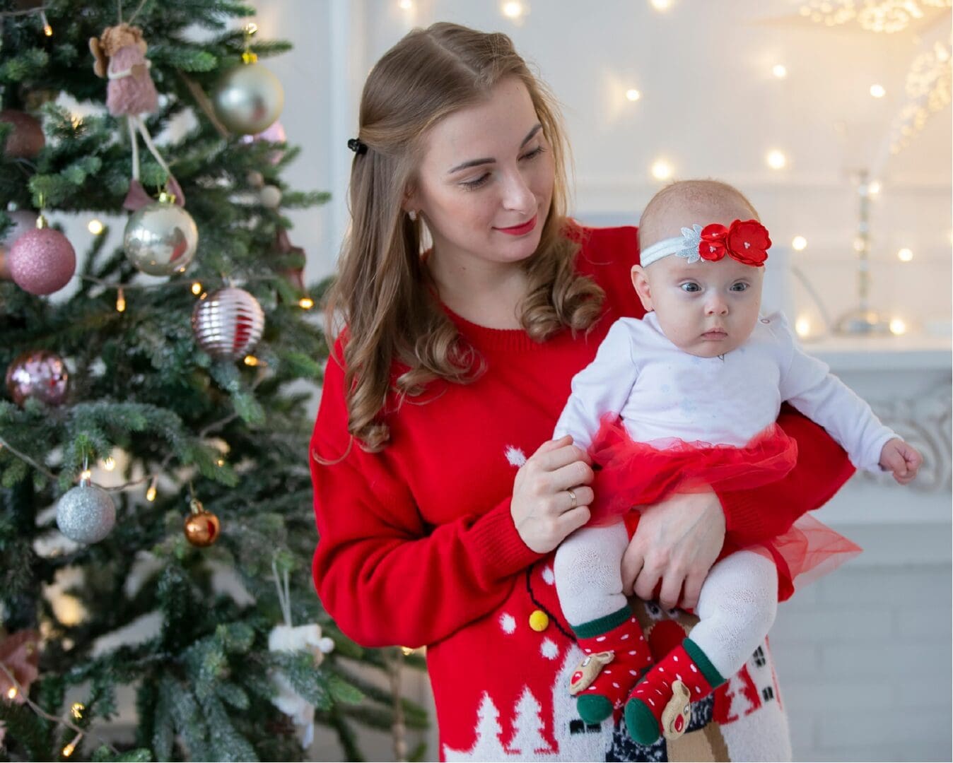 An author, known for her children's books, capturing a heartwarming moment of a woman holding a baby in front of a Christmas tree.